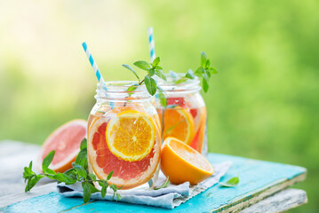 Grapefruit and orange water in glass jars in the open air. Concept for healthy eating and...