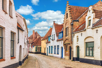 Fototapeta na wymiar Vintage street in Bruges Belgium with blue sky and white cloud. Europe landscape panorama old town.