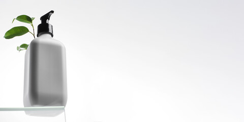 Organic cosmetic product in a white dispenser with green leaves. Zero west concept, recycling. Copy space