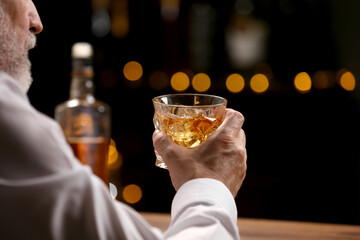Senior man with glass of whiskey at bar counter, closeup