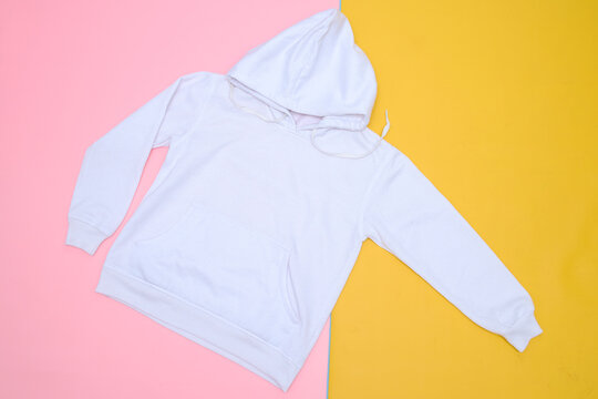 White fashionable sweatshirt with a hood on colorful background top view. Blank hoody mock up 