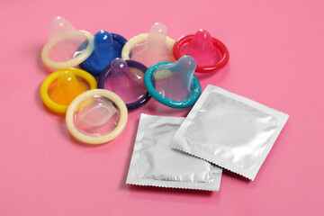 Unpacked condoms and packages on pink background. Safe sex