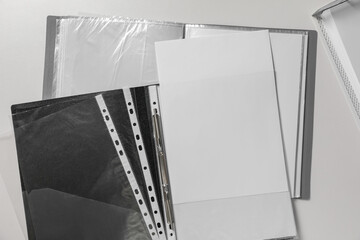 Folders with punched pockets on white table, flat lay