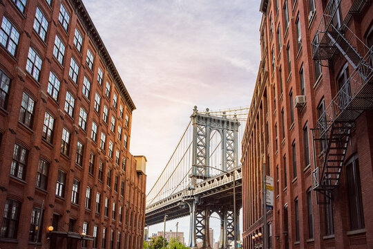 Manhattan Bridge between Manhattan and Brooklyn over East River seen from a narrow alley enclosed by two brick buildings on a sunny day, New York City