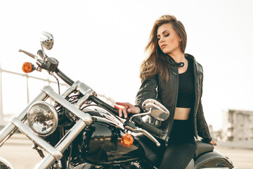 Fototapeta na wymiar Girl on a motorcycle. She is beautiful, posing on a motorcycle at sunset