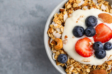 Tasty granola, yogurt and fresh berries in bowl on light grey table, top view with space for text....