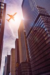 plane flying over futuristic glass and steel office towers in the sun, Manhattan, New York City