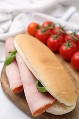 Delicious sandwich with ham and basil on table, closeup