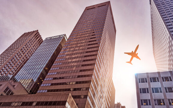 plane flying over futuristic glass and steel office towers in the sun, Manhattan, New York City