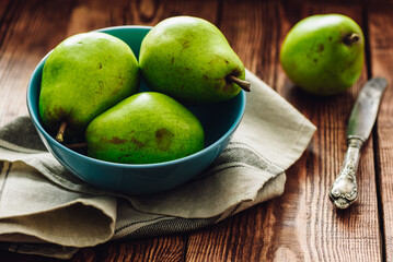Green Pears in Blue Bowl and Knife on Table.