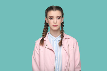 Portrait of serious strict young teenager girl with braids wearing pink jacket looking at camera...