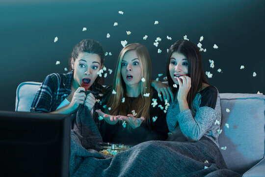 Teenage Girls Watching Horror Movie With Popcorn