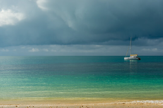 A gloomy sky above the turquoise calm sea and a small white yacht