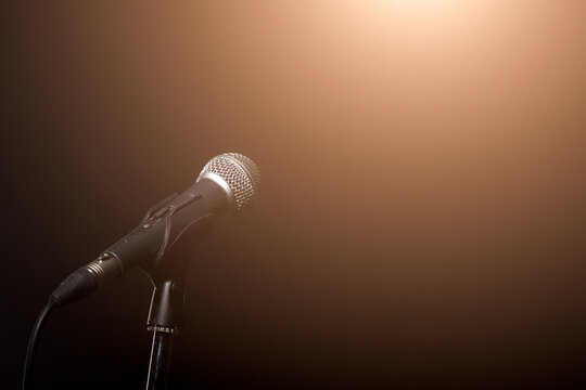 Photo of microphone in light of spotlight on empty black background