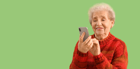 Senior woman using mobile phone on green background with space for text