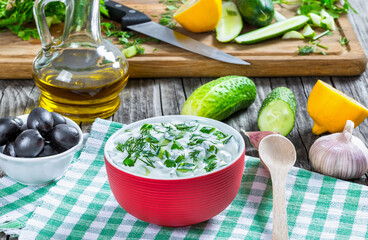 Tzatziki sauce, cucumber, bottle of olive oil on a green napkin against the background of a cutting board