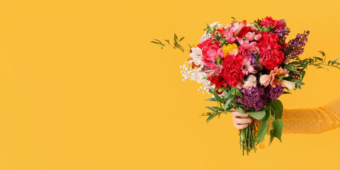 Female hand with beautiful bouquet on yellow background with space for text