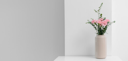 Vase with beautiful carnation flowers on light table in room. Banner for design