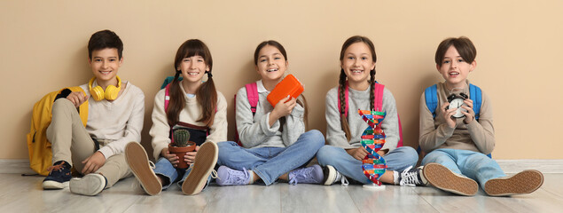 Many little students sitting near beige wall