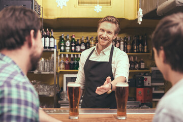 Football time. Friends spending time together in pub. Guys having fun while drinking beer. Barman looking at camera