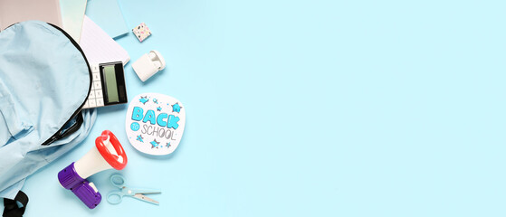 Megaphone, school backpack and stationery on light blue background with space for text