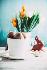 Easter. Chocolate  Eggs and bunny on Easter table. Tulips in vase. Easter setting  on table