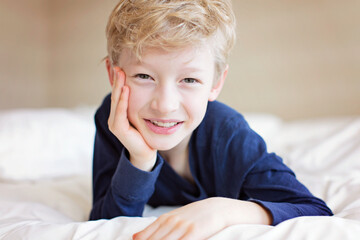 Fototapeta premium beautiful laughing boy lying in the bed being playful and happy, positive emotion concept