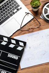 Fototapeta premium Storyboard with movie clapper, laptop and eyeglasses on wooden background