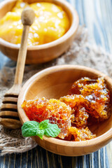 Honey in a wooden bowls and honey dipper on an old rustic table, selective focus.