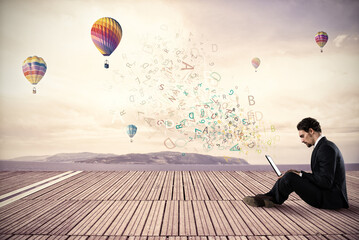 Businessman working with his laptop on background hot air balloons in the sky