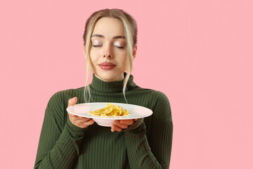 Young woman with tasty pasta on pink background