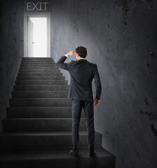 Businessman looks at the exit at the end of the stairs. Exit from business stress and financial crisis