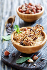 Honey cereal bars with chocolate in bowls on old wooden table, selective focus.
