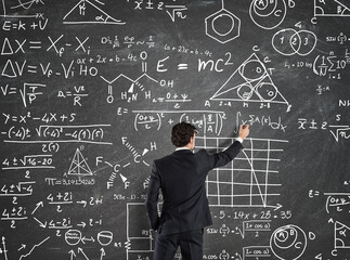 Businessman trying to solve problems with Math calculations on the blackboard