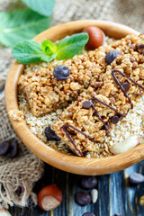 Cereal bars in a bowl with oat flakes on wooden table, selective focus.