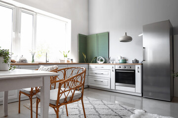 Interior of light kitchen with stylish fridge, counters, table and chairs