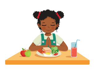 Little African girl praying before eating breakfast at the table