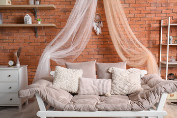 Interior of modern living room with sofa and dream catcher hanging on brick wall
