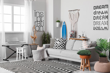 Interior of stylish living room with surfboard, synthesizer and sofa