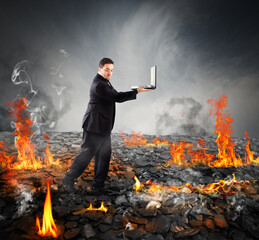 Businessman with pc walking on burning charcoal