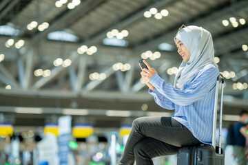 An Asian Muslim wearing a blue hijab is preparing for a vacation and she is at the airport. She is...