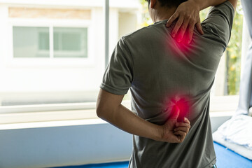 Shoulder pain and back from office syndrome An Asian man touches his neck and back shoulders until...
