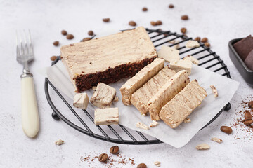 Grid with pieces of tasty marble halva on light background