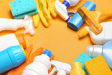 Frame made of different cleaning supplies on orange background, closeup