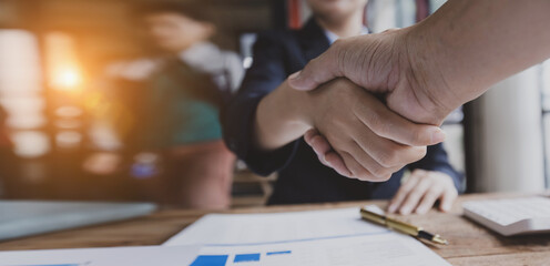 Business woman shaking hands and finishing up meeting at desk in office.