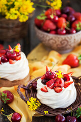 Delicious mini Pavlova meringue cake decorated with fresh strawberry and cherry