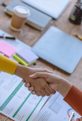 Naklejka premium Business people shaking hands and finishing up meeting at desk in office.