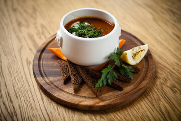 Saltwort russian beef, pork and sausage soup solyanka with lemon, salami in plate on wood background