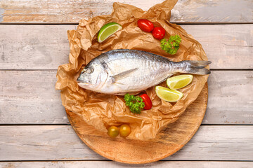 Board of raw dorado fish with lime and tomatoes on grey wooden background
