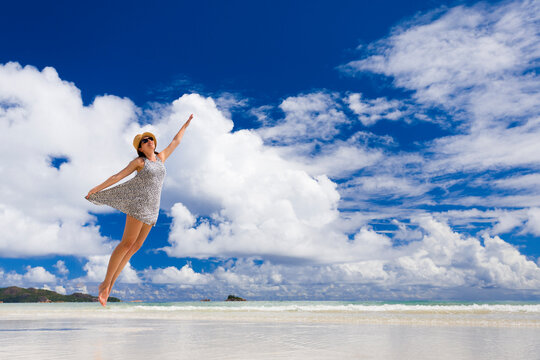 Beautiful woman jumping on the wonderful beach of Praslin, Seychelles